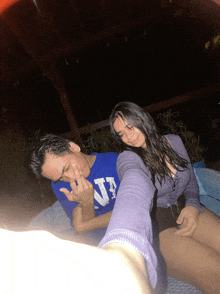 a man wearing a blue shirt with the letter n on it sits next to a woman in a purple top