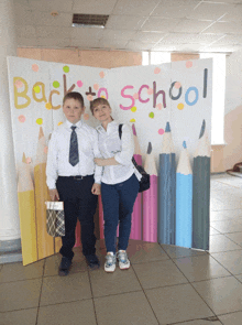 two people standing in front of a back to school sign