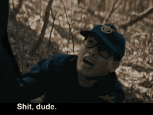 a man wearing glasses and a blue hat says " shit dude "