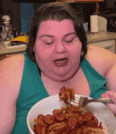 a woman in a blue tank top is eating a bowl of food
