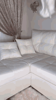 a white leather sectional couch with pillows and a rug