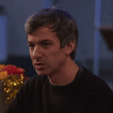 a man wearing a black sweater is sitting at a table