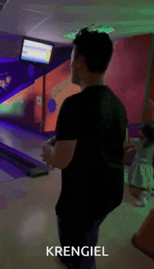 a man in a black shirt is standing in a bowling alley and the name krengiel is on the bottom