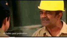a man wearing a hard hat talks to another man