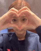 a girl making a heart with her hands in front of her face