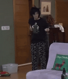 a person is dancing in a living room with a couch and a pillow that says merry christmas .
