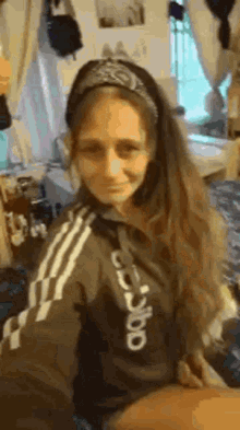 a woman wearing a headband and a hoodie is taking a selfie in a room .