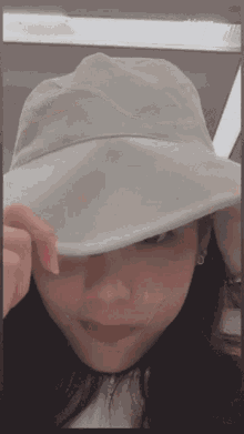 a woman wearing a white hat covering her face with her hand