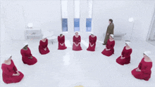 a group of women in red dresses sit in a circle on the floor