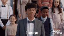 a man in a suit says goodbye in front of a group of children
