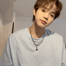 a young man wearing a light blue t-shirt and a necklace