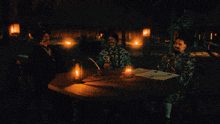 three men sit at a table with candles and the words what 's a clitoris