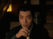 a man is drinking a glass of wine in the dark .