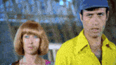 a man in a yellow shirt is standing next to a woman in a pink dress