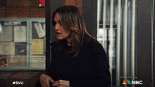 a woman in a black jacket is standing in front of a nbc sign