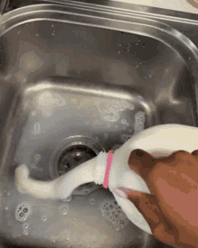 a person is washing a bottle in a sink