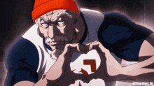 a man wearing an orange beanie is making a heart shape