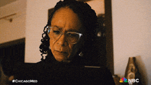 a woman wearing glasses is looking at a laptop with the hashtag #chicagomed on the bottom