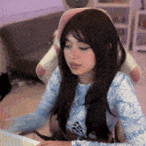 a woman wearing a blue and white shirt with the word virgo on it is sitting at a desk