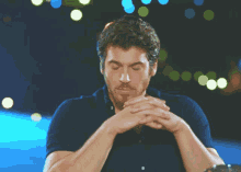 a man with his eyes closed and his hands folded in prayer