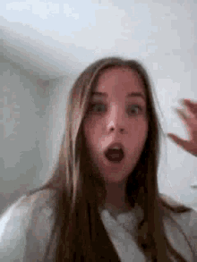 a girl with long hair is making a funny face with her mouth wide open .