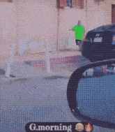 a man in a green shirt is walking down a sidewalk in front of a building .