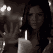 a woman reaches out to touch a lit candle