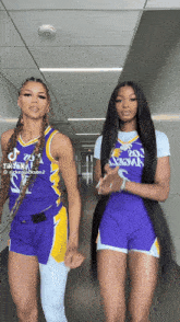 two women standing next to each other in a hallway with one wearing a jersey that says lakers