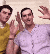 a man in a purple shirt is sitting next to another man in a yellow sweater .