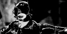 a black and white photo of catwoman drinking from a glass .