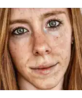 a close up of a woman 's face with green eyes and red hair