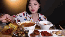a woman is sitting at a table eating a bowl of food with chopsticks .