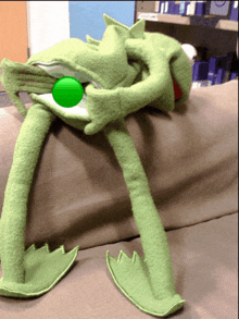 a stuffed green frog with a green ball in its mouth