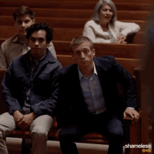 a man in a suit sits in a church with shameless showing on the bottom