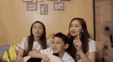 three people are sitting on a couch and one of them is pointing up at the camera .