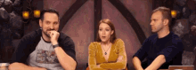 a man and two women are sitting at a table talking