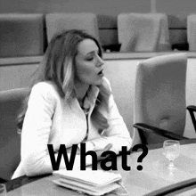 a black and white photo of a woman sitting at a table with the words " what " written above her