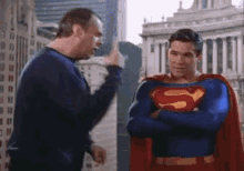 a man in a superman costume is talking to another man .