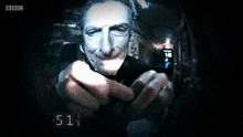 a bbc screen shows a man with a gun pointing at the camera