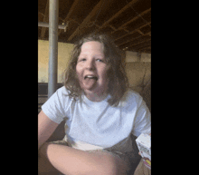 a young girl in a white shirt is sticking her tongue out and holding a box of cheerios
