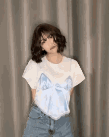 a young woman wearing a white t-shirt and blue shorts is posing for a picture .