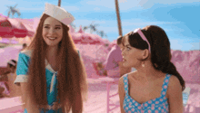 two women are standing next to each other and one is wearing a white hat