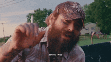 a man with a beard is wearing a hat that says ' before i kiss ' on it
