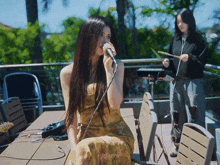 a woman in a yellow dress singing into a microphone with the name njefaerie on the bottom right