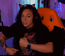 a woman wearing headphones and a cat ear headband is sitting next to a stuffed animal .