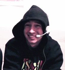a man wearing headphones and a hoodie with the letter a on it smiles