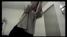 a person in a white shirt is standing in a room with their arms outstretched .