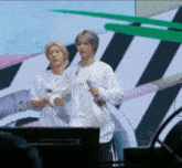 a couple of men standing next to each other on a stage holding a microphone .