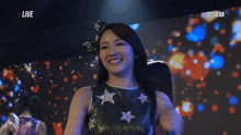 a woman holding a microphone in front of a screen that says live on it