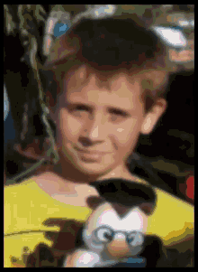a boy in a yellow shirt is holding a stuffed animal with glasses